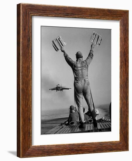 Shot of a Man Using Hand Lights to Signal an Incoming Aircraft Towards the Carrier's Landing-Hank Walker-Framed Photographic Print