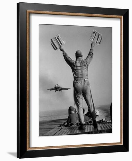 Shot of a Man Using Hand Lights to Signal an Incoming Aircraft Towards the Carrier's Landing-Hank Walker-Framed Photographic Print