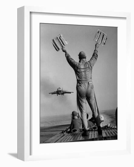Shot of a Man Using Hand Lights to Signal an Incoming Aircraft Towards the Carrier's Landing-Hank Walker-Framed Photographic Print