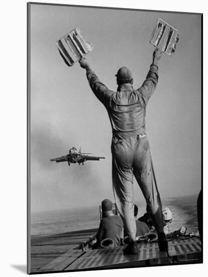 Shot of a Man Using Hand Lights to Signal an Incoming Aircraft Towards the Carrier's Landing-Hank Walker-Mounted Photographic Print