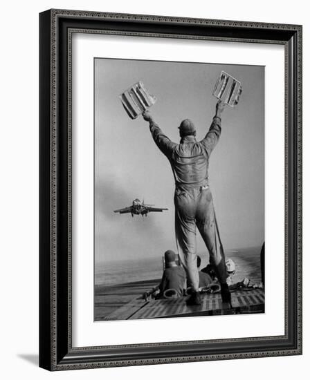 Shot of a Man Using Hand Lights to Signal an Incoming Aircraft Towards the Carrier's Landing-Hank Walker-Framed Photographic Print