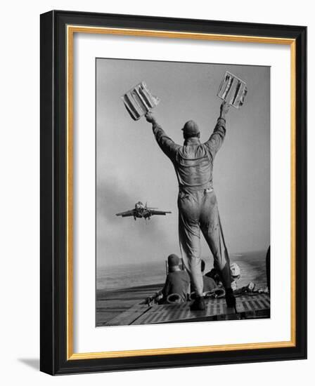 Shot of a Man Using Hand Lights to Signal an Incoming Aircraft Towards the Carrier's Landing-Hank Walker-Framed Photographic Print