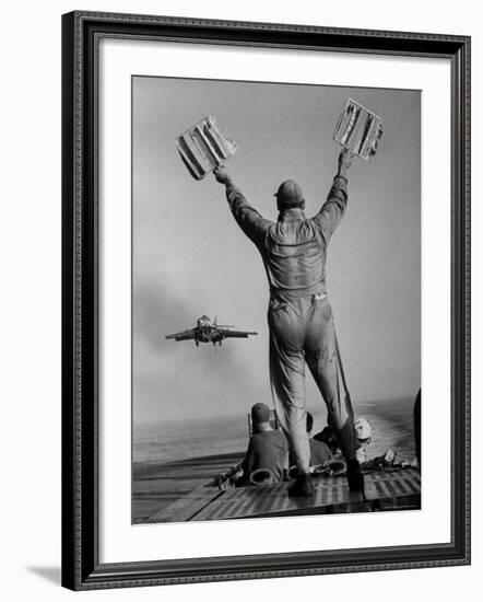 Shot of a Man Using Hand Lights to Signal an Incoming Aircraft Towards the Carrier's Landing-Hank Walker-Framed Photographic Print