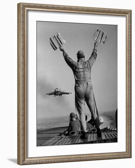 Shot of a Man Using Hand Lights to Signal an Incoming Aircraft Towards the Carrier's Landing-Hank Walker-Framed Photographic Print