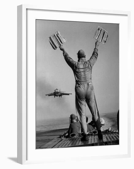 Shot of a Man Using Hand Lights to Signal an Incoming Aircraft Towards the Carrier's Landing-Hank Walker-Framed Photographic Print