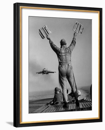 Shot of a Man Using Hand Lights to Signal an Incoming Aircraft Towards the Carrier's Landing-Hank Walker-Framed Photographic Print