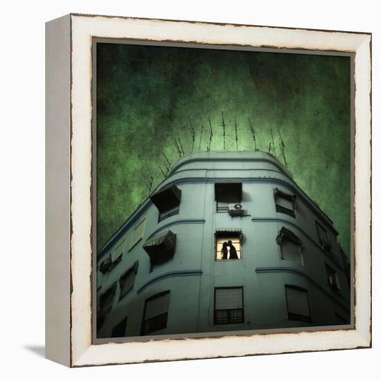 Silhouette of a Man and Woman Kissing in a Window of a Large Building with TV Ariels on the Roof-Luis Beltran-Framed Premier Image Canvas