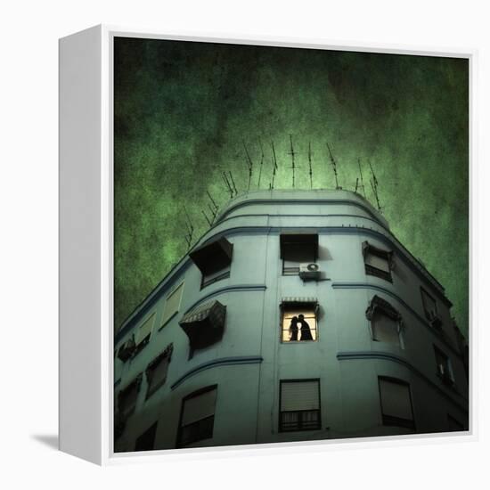 Silhouette of a Man and Woman Kissing in a Window of a Large Building with TV Ariels on the Roof-Luis Beltran-Framed Premier Image Canvas