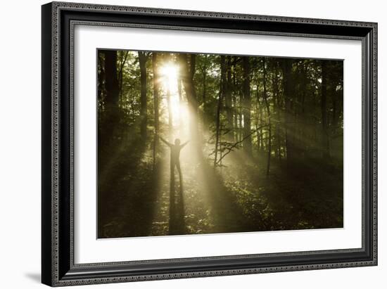 Silhouette of a Man Standing in the Sunrays of a Dark, Misty Forest, Denmark-null-Framed Photographic Print