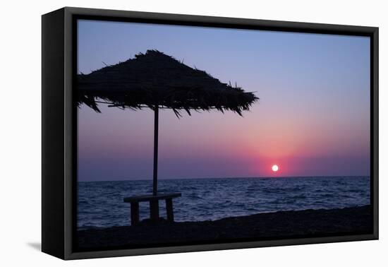 Silhouette of an excited man jumping on black sand beach early morning sunrise in Santorini, Greece-Michele Niles-Framed Premier Image Canvas