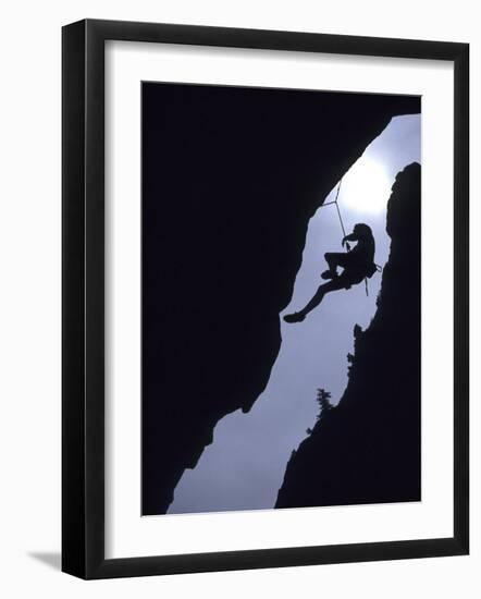 Silhouette of Rock Climber Hanging from Cliff Face--Framed Photographic Print