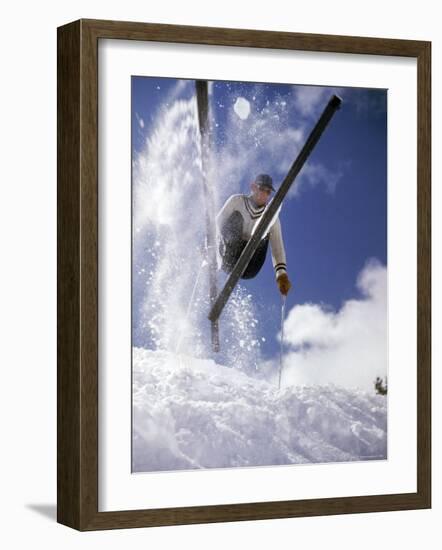 Skier Kicking Up Powder as He Jumps over Hill-George Silk-Framed Photographic Print