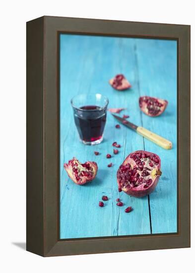 Sliced Pomegranate and a Glass of Pomegranate Juice on Turquoise Wooden Table-Jana Ihle-Framed Premier Image Canvas