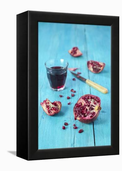 Sliced Pomegranate and a Glass of Pomegranate Juice on Turquoise Wooden Table-Jana Ihle-Framed Premier Image Canvas