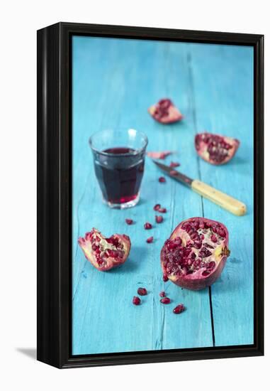 Sliced Pomegranate and a Glass of Pomegranate Juice on Turquoise Wooden Table-Jana Ihle-Framed Premier Image Canvas