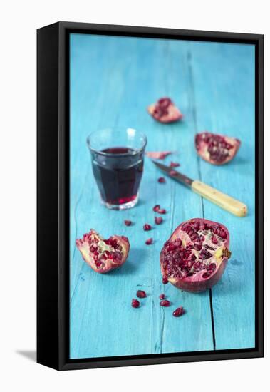 Sliced Pomegranate and a Glass of Pomegranate Juice on Turquoise Wooden Table-Jana Ihle-Framed Premier Image Canvas