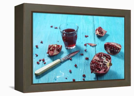 Sliced Pomegranate and a Glass of Pomegranate Juice on Turquoise Wooden Table-Jana Ihle-Framed Premier Image Canvas