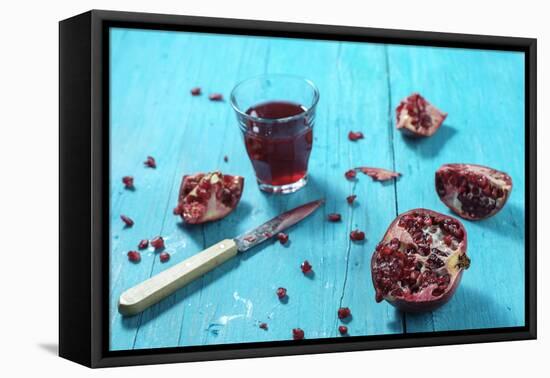 Sliced Pomegranate and a Glass of Pomegranate Juice on Turquoise Wooden Table-Jana Ihle-Framed Premier Image Canvas