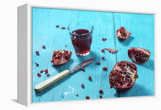 Sliced Pomegranate and a Glass of Pomegranate Juice on Turquoise Wooden Table-Jana Ihle-Framed Premier Image Canvas