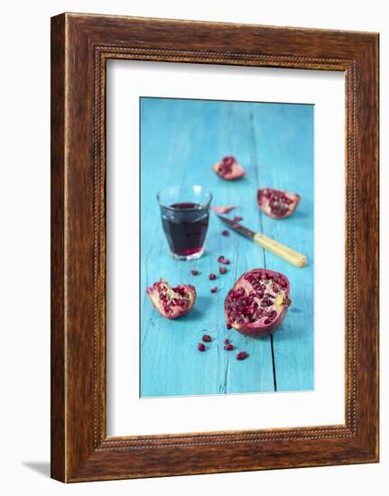 Sliced Pomegranate and a Glass of Pomegranate Juice on Turquoise Wooden Table-Jana Ihle-Framed Photographic Print