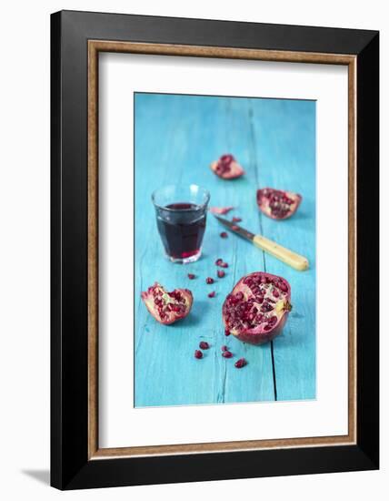 Sliced Pomegranate and a Glass of Pomegranate Juice on Turquoise Wooden Table-Jana Ihle-Framed Photographic Print