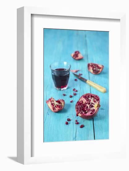 Sliced Pomegranate and a Glass of Pomegranate Juice on Turquoise Wooden Table-Jana Ihle-Framed Photographic Print