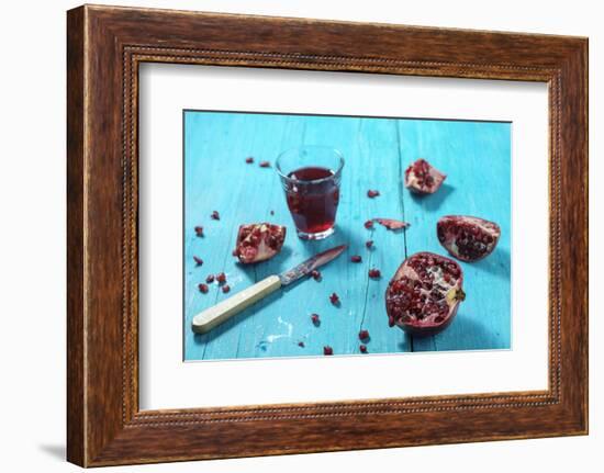 Sliced Pomegranate and a Glass of Pomegranate Juice on Turquoise Wooden Table-Jana Ihle-Framed Photographic Print