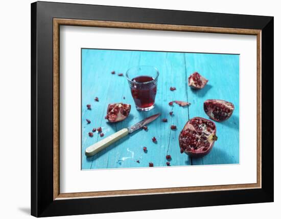 Sliced Pomegranate and a Glass of Pomegranate Juice on Turquoise Wooden Table-Jana Ihle-Framed Photographic Print