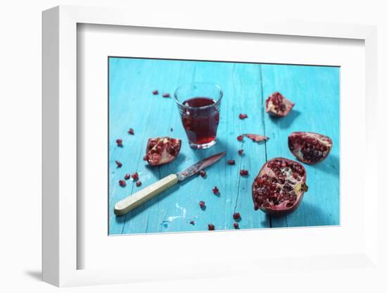 Sliced Pomegranate and a Glass of Pomegranate Juice on Turquoise Wooden Table-Jana Ihle-Framed Photographic Print