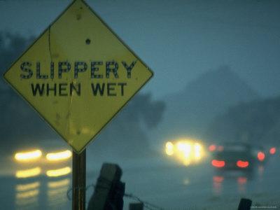 &lsquo;Slippery When Wet Sign in Fore with Traffic in Background in Rain on