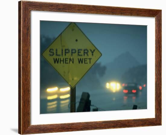 Slippery When Wet Sign in Fore with Traffic in Background in Rain on California Highway 14-Ralph Crane-Framed Photographic Print