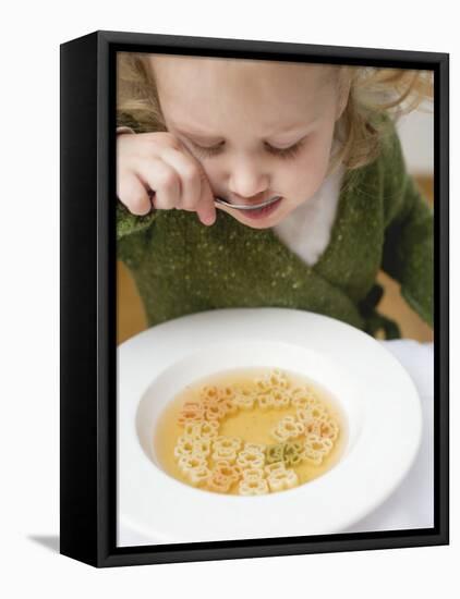 Small Girl Eating Soup with Teddy Bear Pasta-null-Framed Premier Image Canvas