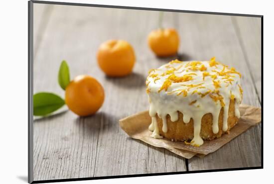 Small Orange Cake with White Icing on Wooden Table-Jana Ihle-Mounted Photographic Print