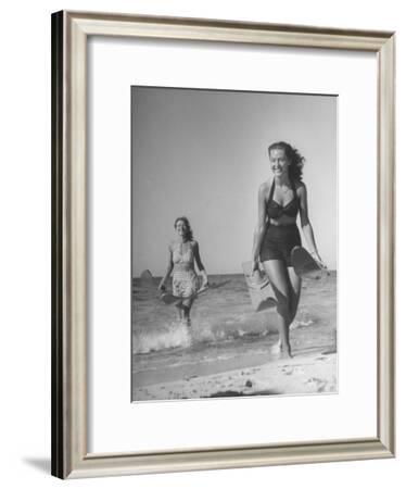 Smiling Girls Carrying Skis Out of the Water onto Beach Photographic ...