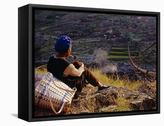 Smoking Her Pipe, a Naxi Woman Rests after Crossing a Precarious Pipe Bridge High Above the Yangtse-Amar Grover-Framed Premier Image Canvas