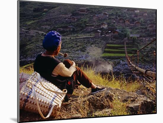 Smoking Her Pipe, a Naxi Woman Rests after Crossing a Precarious Pipe Bridge High Above the Yangtse-Amar Grover-Mounted Photographic Print