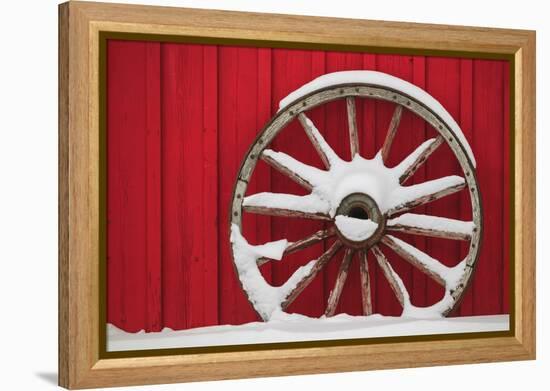 Snow-covered wagon wheels against red barn near town of Banff, Canadian Rockies, Alberta, Canada-Stuart Westmorland-Framed Premier Image Canvas