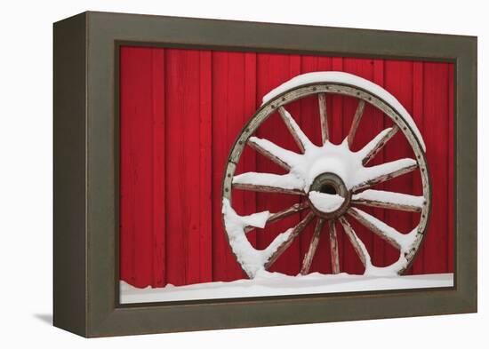 Snow-covered wagon wheels against red barn near town of Banff, Canadian Rockies, Alberta, Canada-Stuart Westmorland-Framed Premier Image Canvas