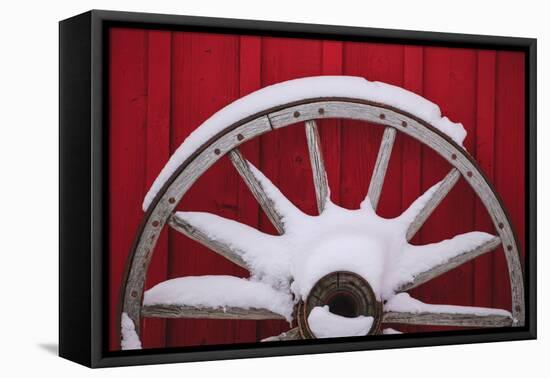 Snow-covered wagon wheels against red barn near town of Banff, Canadian Rockies, Alberta, Canada-Stuart Westmorland-Framed Premier Image Canvas