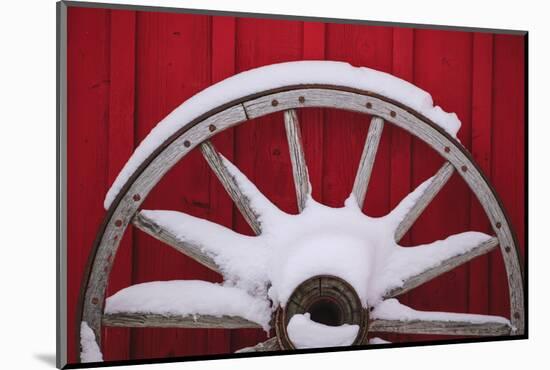 Snow-covered wagon wheels against red barn near town of Banff, Canadian Rockies, Alberta, Canada-Stuart Westmorland-Mounted Photographic Print