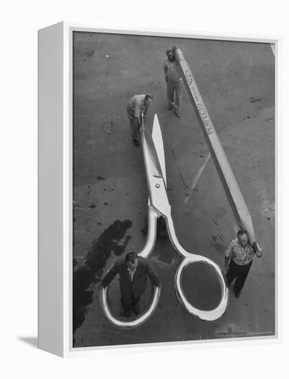 Stagehands Pushing a Pair of Gigantic Scissors on a Dollie Next to Two Men Carrying a 21 Ft. Pencil-Allan Grant-Framed Premier Image Canvas