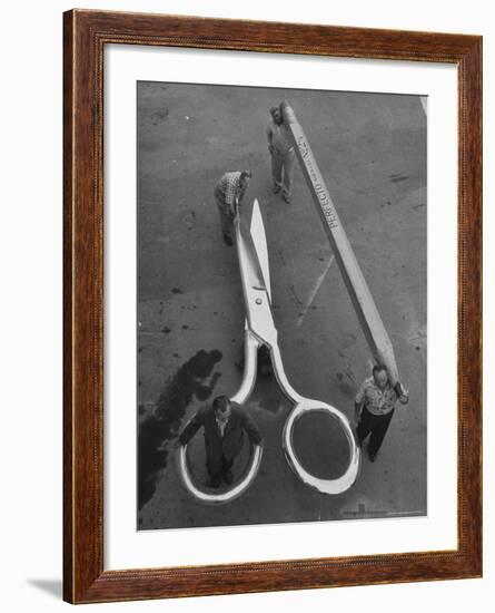 Stagehands Pushing a Pair of Gigantic Scissors on a Dollie Next to Two Men Carrying a 21 Ft. Pencil-Allan Grant-Framed Photographic Print