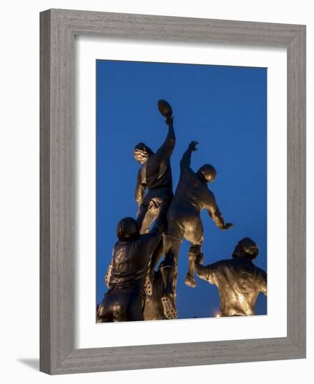 Statue of rugby players is illuminated at dusk outside Twickenham Stadium, London-Charles Bowman-Framed Photographic Print