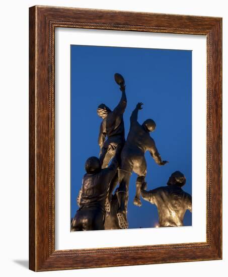 Statue of rugby players is illuminated at dusk outside Twickenham Stadium, London-Charles Bowman-Framed Photographic Print