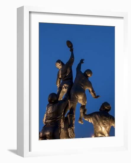 Statue of rugby players is illuminated at dusk outside Twickenham Stadium, London-Charles Bowman-Framed Photographic Print