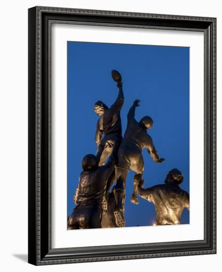 Statue of rugby players is illuminated at dusk outside Twickenham Stadium, London-Charles Bowman-Framed Photographic Print