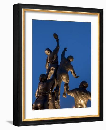 Statue of rugby players is illuminated at dusk outside Twickenham Stadium, London-Charles Bowman-Framed Photographic Print