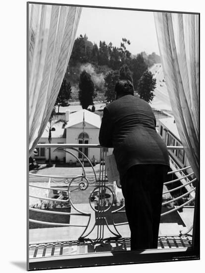 Suit Clad Movie Director Alfred Hitchcock as He Leans on Balcony Railing of Apartment-Peter Stackpole-Mounted Premium Photographic Print