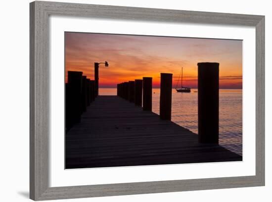 Sunrise on the Water with an Empty Dock and a Sailboat in the Distance of Tilghman Island, Maryland-Karine Aigner-Framed Photographic Print