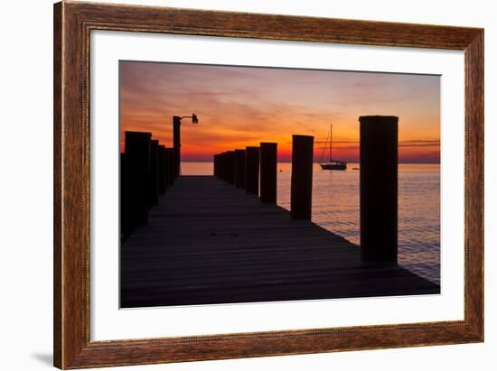 Sunrise on the Water with an Empty Dock and a Sailboat in the Distance of Tilghman Island, Maryland-Karine Aigner-Framed Photographic Print